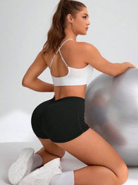 Woman in athletic wear posing with a fitness ball on a plain background