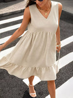 Woman wearing a beige sleeveless dress crossing a street.