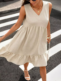 Woman wearing a beige sleeveless dress crossing a street.