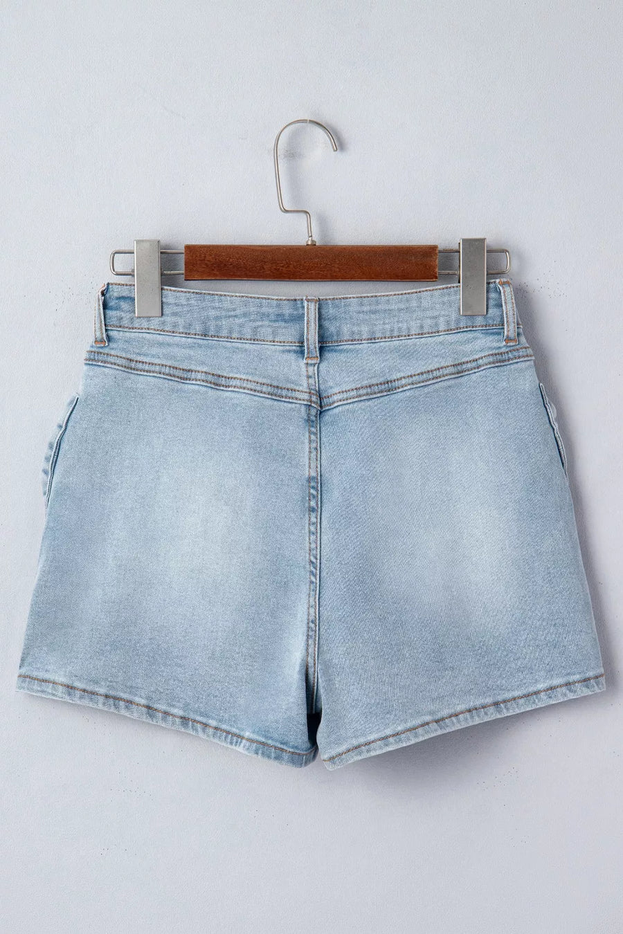 Light blue denim shorts on a hanger against a white background