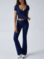 Woman wearing a navy blue outfit with a top and flared pants on a white background