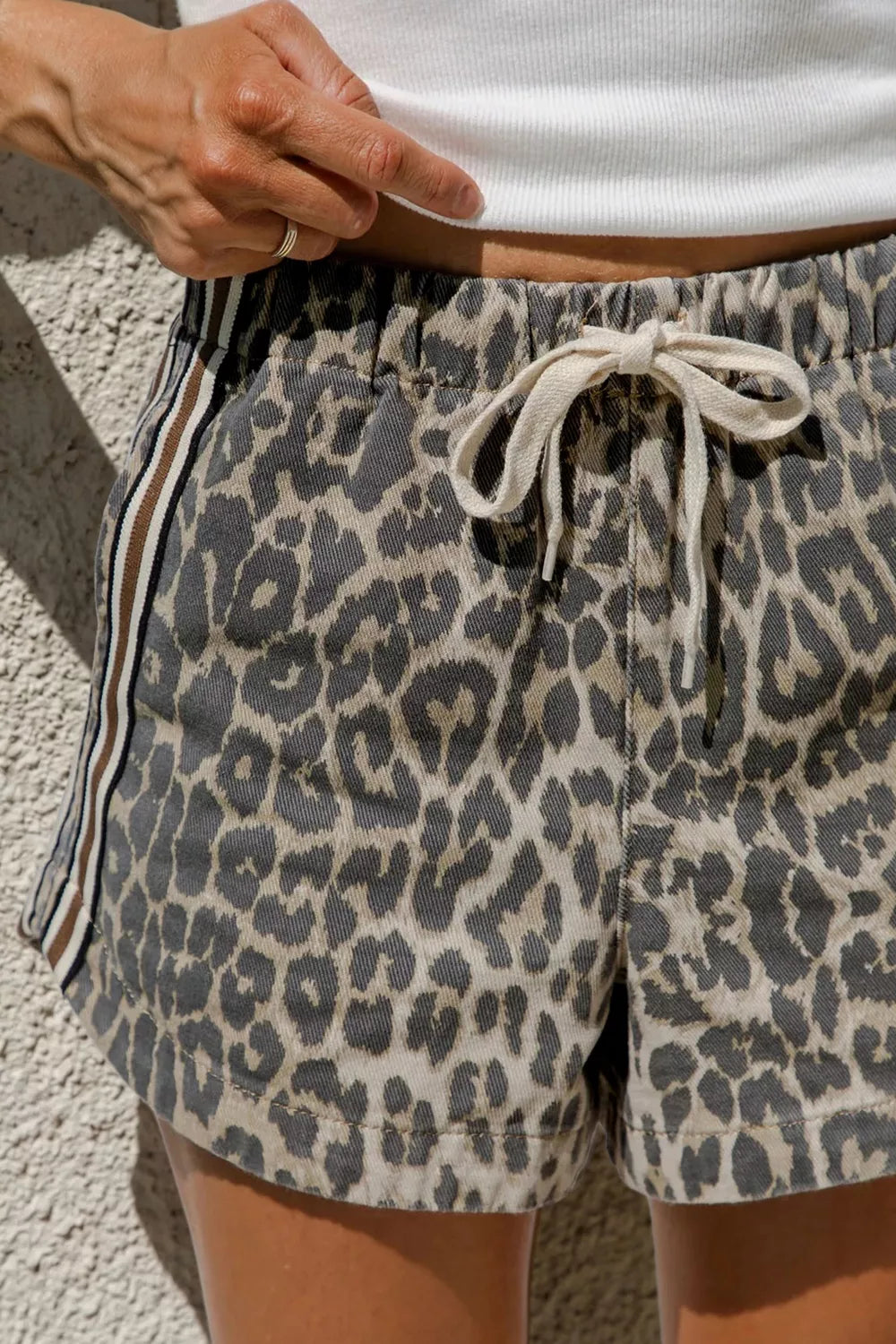 Leopard print shorts with drawstring waistband worn by a person against a neutral background