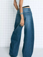 Person wearing blue wide-leg jeans against a grid-patterned wall.