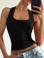 Person wearing a black tank top and blue jeans against a neutral background