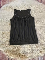 Black tank top with button details on a fluffy white rug