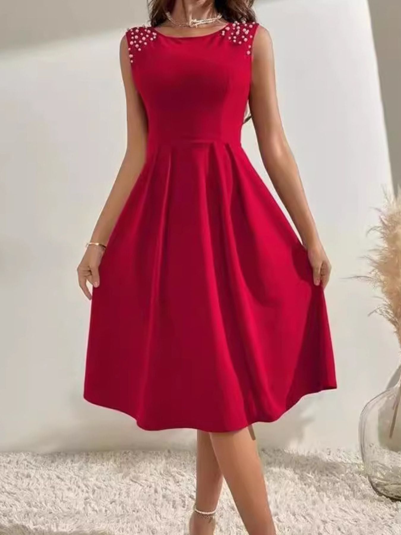 Red dress with beaded shoulders on a plain background