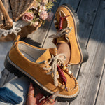 Brown leather shoes with decorative elements on a wooden surface