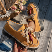 Brown leather shoes with decorative elements on a wooden surface