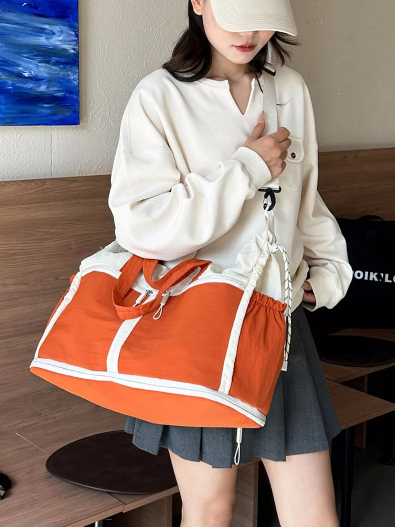 Person holding an orange and white bag indoors