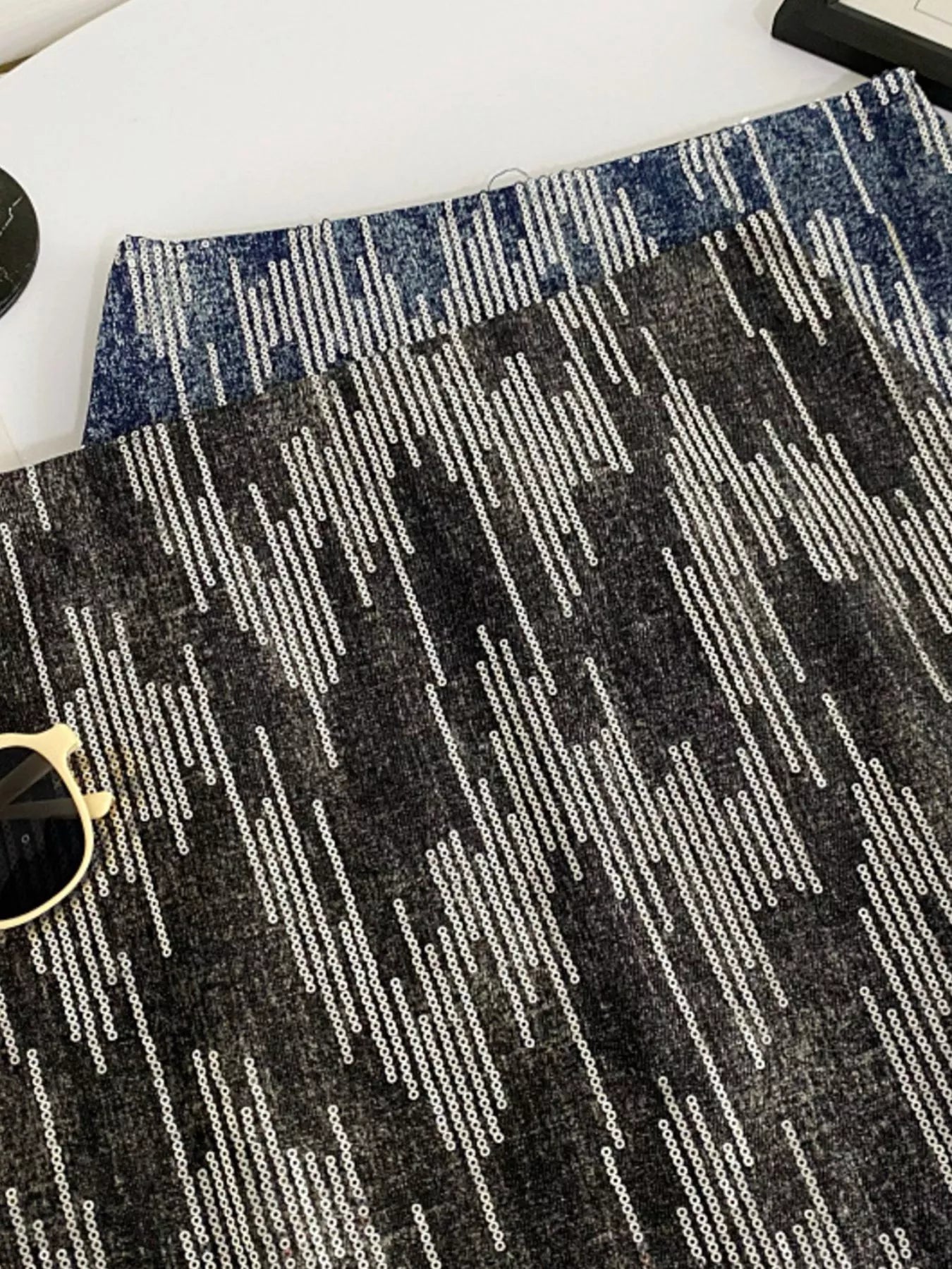 Close-up of a textured black and gray patterned rug with sunglasses on top.