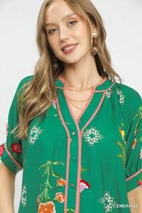 Woman wearing a green floral blouse with pink accents on a white background