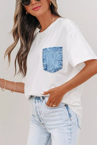 Woman wearing a white t-shirt with a blue pocket design and light blue jeans on a plain background