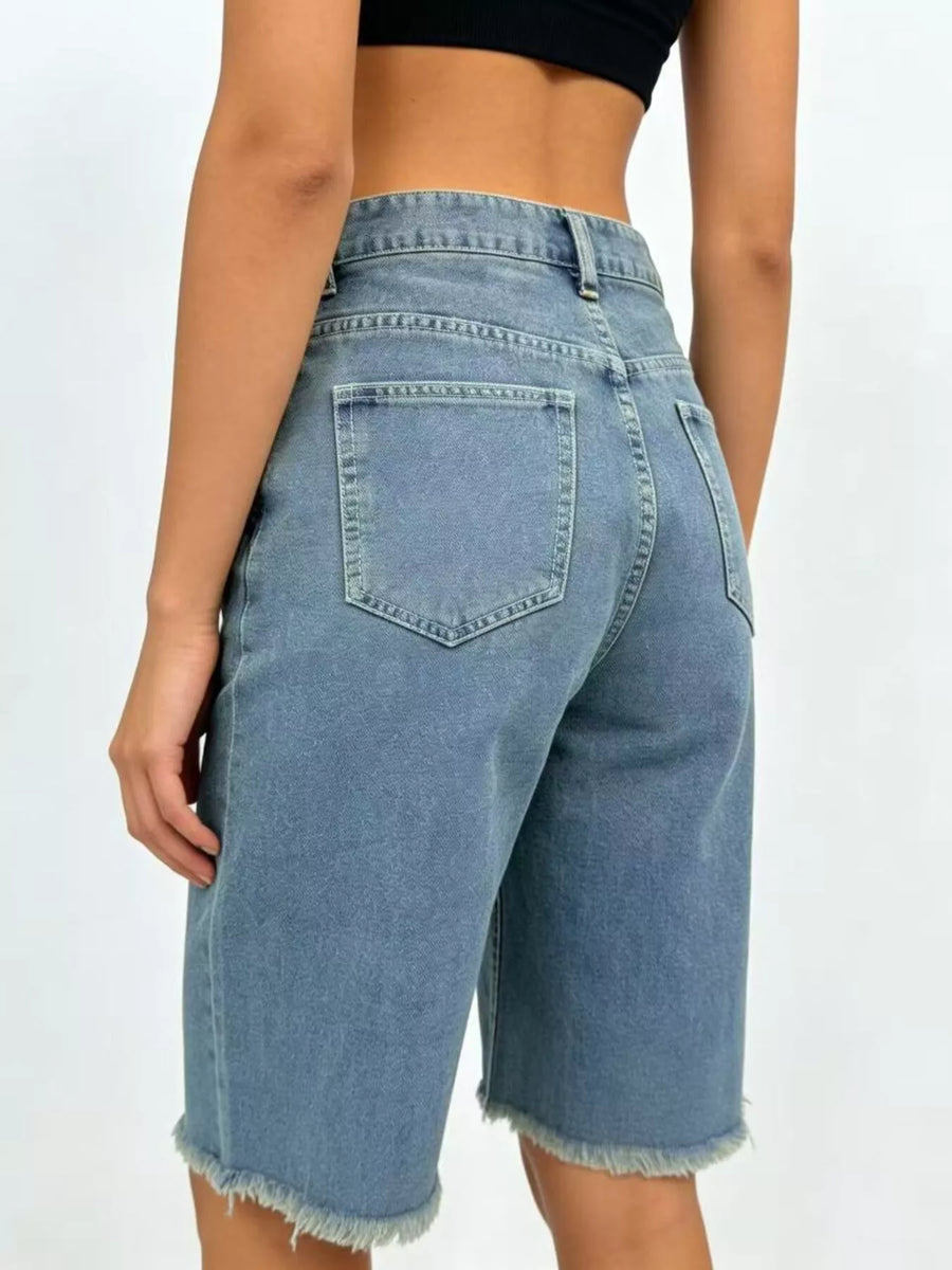 Blue denim shorts worn by a person on a white background