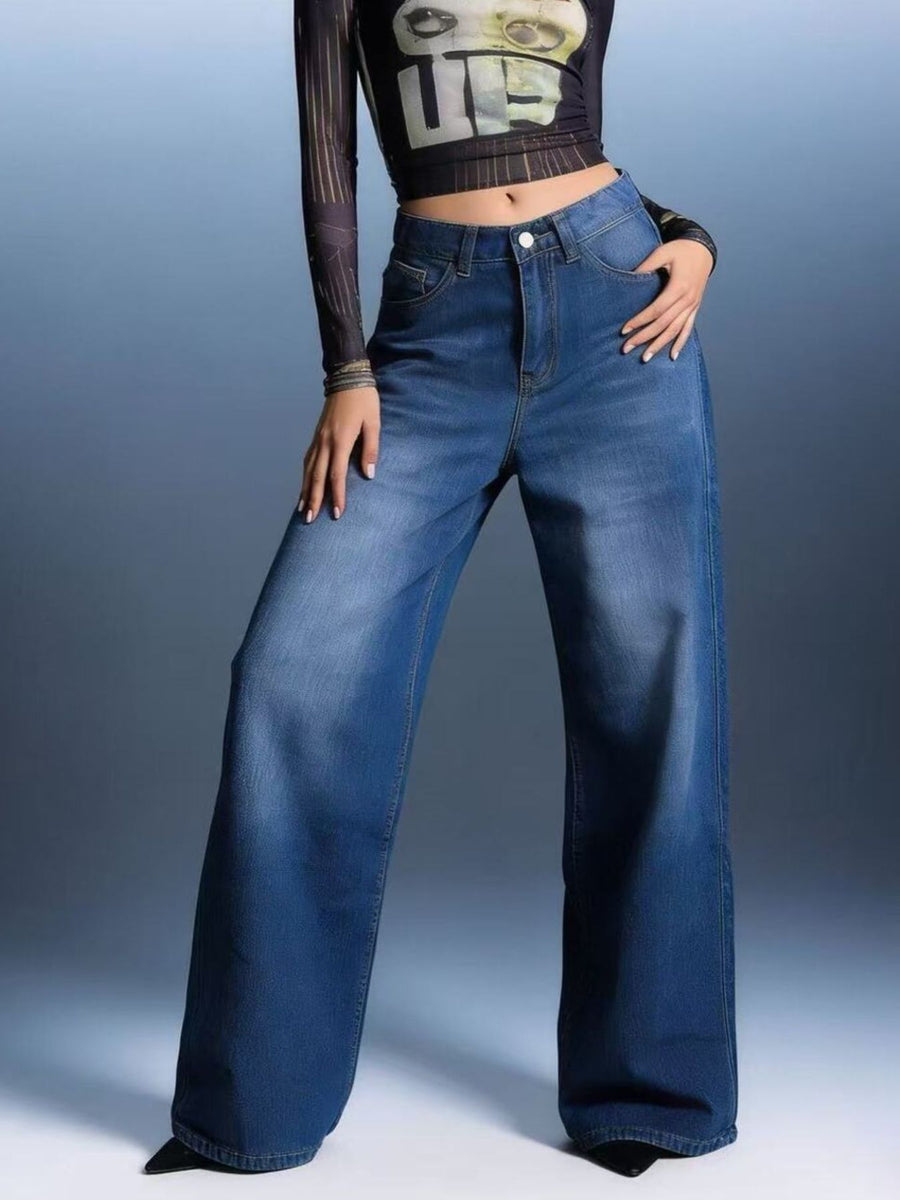 Person wearing blue flared jeans against a gray background