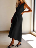 Woman wearing a black sleeveless dress standing indoors near a window.