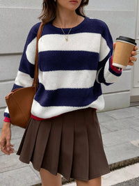 Person wearing a striped sweater and brown skirt, holding a coffee cup.