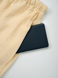Black leather wallet on beige fabric with a white background