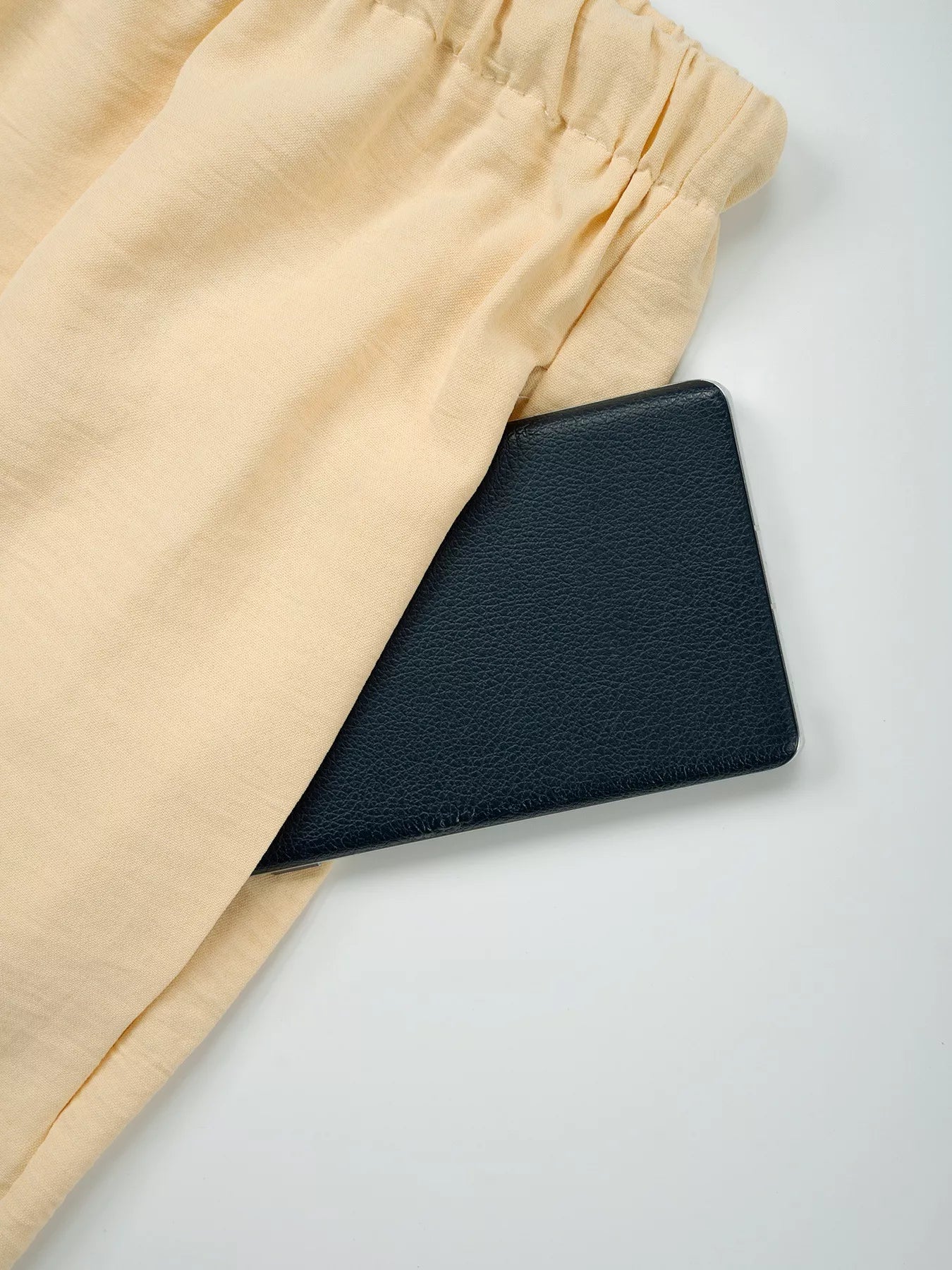 Black leather wallet on beige fabric with a white background