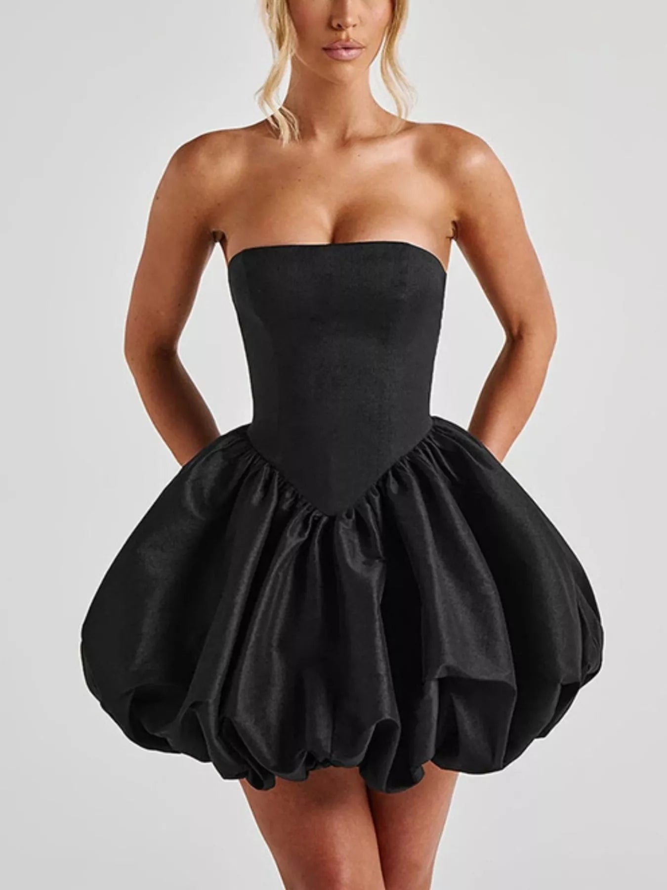 Black strapless dress with a puffy skirt worn by a model on a light gray background