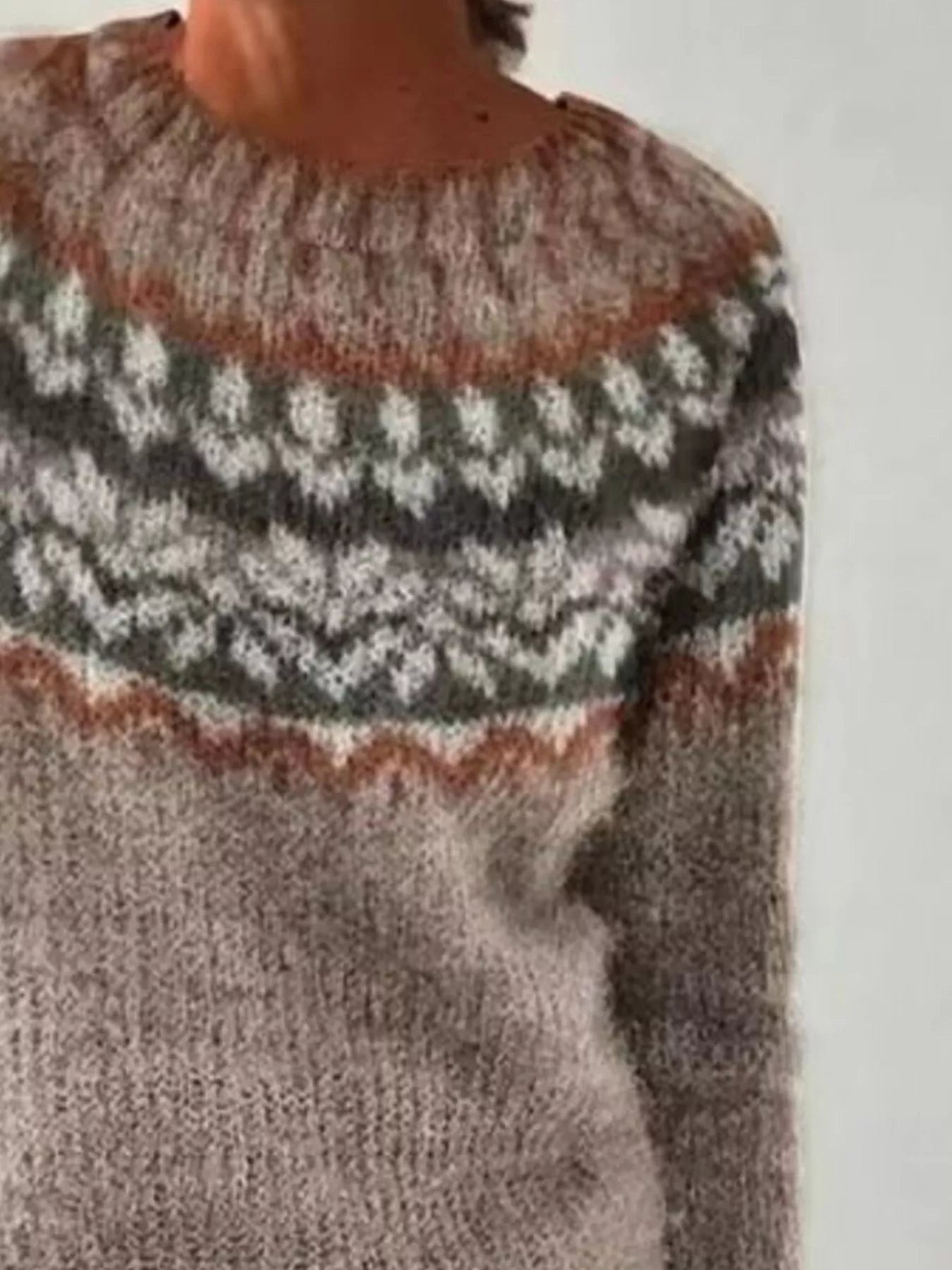 Close-up of a person wearing a patterned sweater with a neutral background