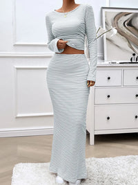 Person wearing a gray and white striped outfit in a room with a dresser and abstract painting.