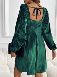 Green velvet dress with open back worn by a person indoors.