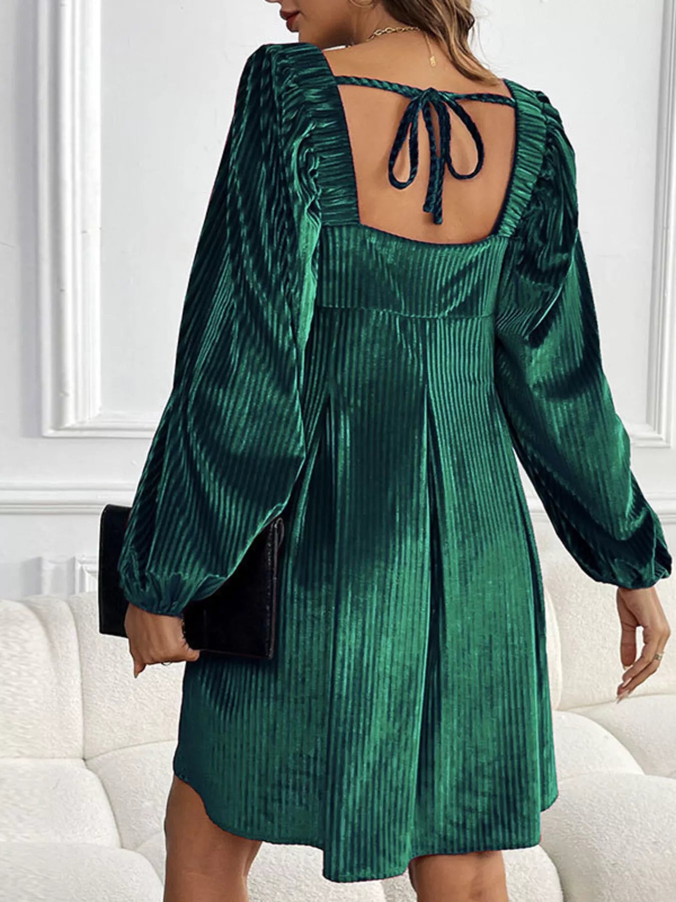 Green velvet dress with open back worn by a person indoors.