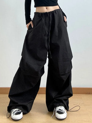 Person wearing black wide-leg pants and black shoes on a light gray background