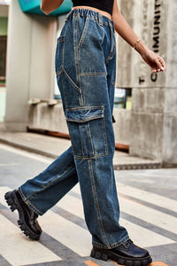 Person wearing blue jeans and black shoes walking on a street.