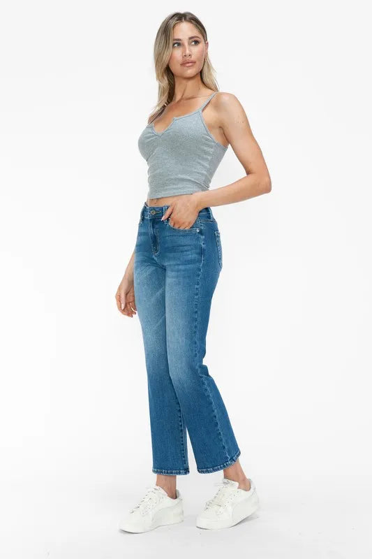 Woman wearing a light gray tank top and blue jeans on a white background