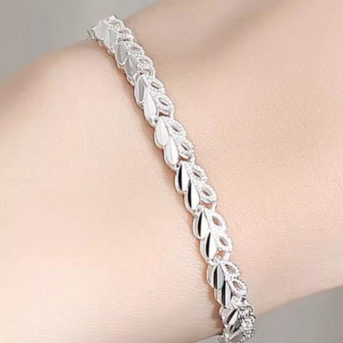 Silver bracelet on a person's wrist with a neutral background