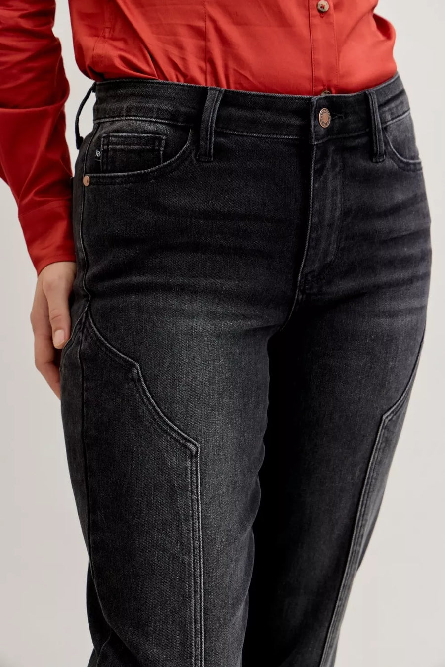 Person wearing black jeans and a red shirt on a light gray background