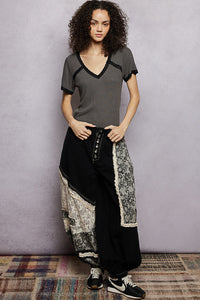 Woman wearing a gray top and black patterned pants against a plain background