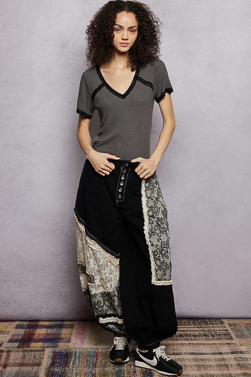 Woman wearing a gray top and black patterned pants against a plain background