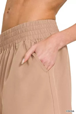 Beige pants with an elastic waistband worn by a person, with a hand in one of the pockets.