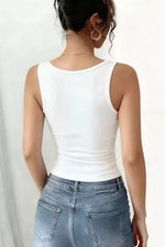 Person wearing a white tank top and blue jeans on a plain background