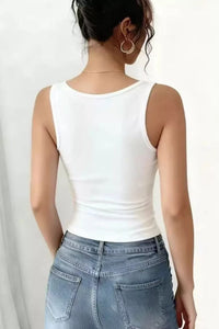 Person wearing a white tank top and blue jeans on a plain background