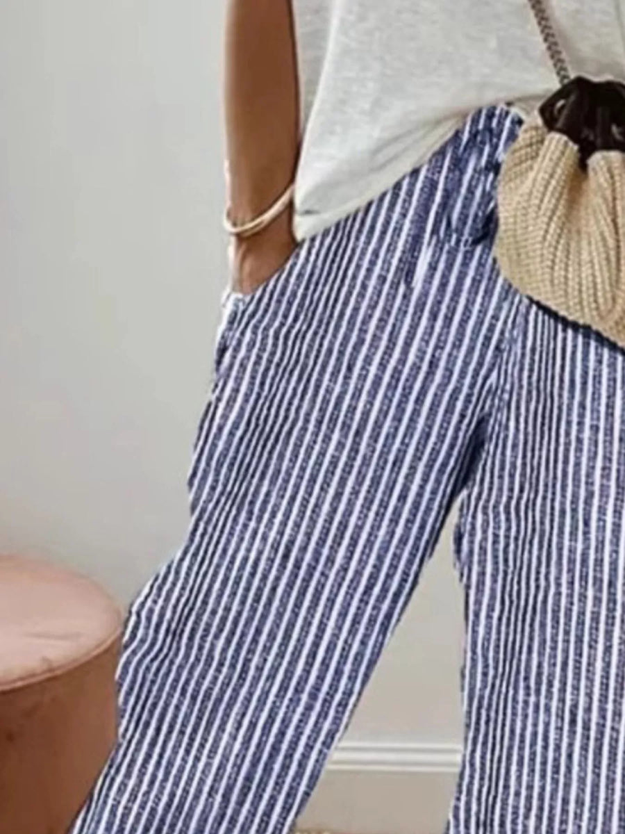 Person wearing blue and white striped pants with a beige bag.