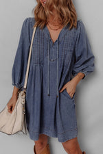 Woman wearing a blue dress with long sleeves against a gray background