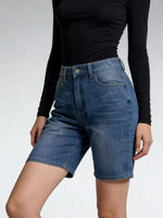 Person wearing blue denim shorts and a black long-sleeve top on a light gray background