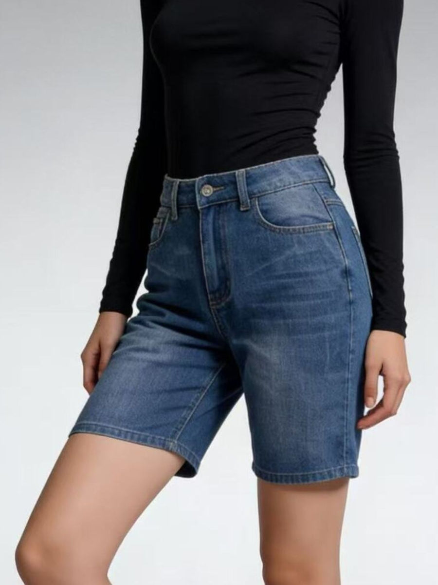 Person wearing blue denim shorts and a black long-sleeve top on a light gray background