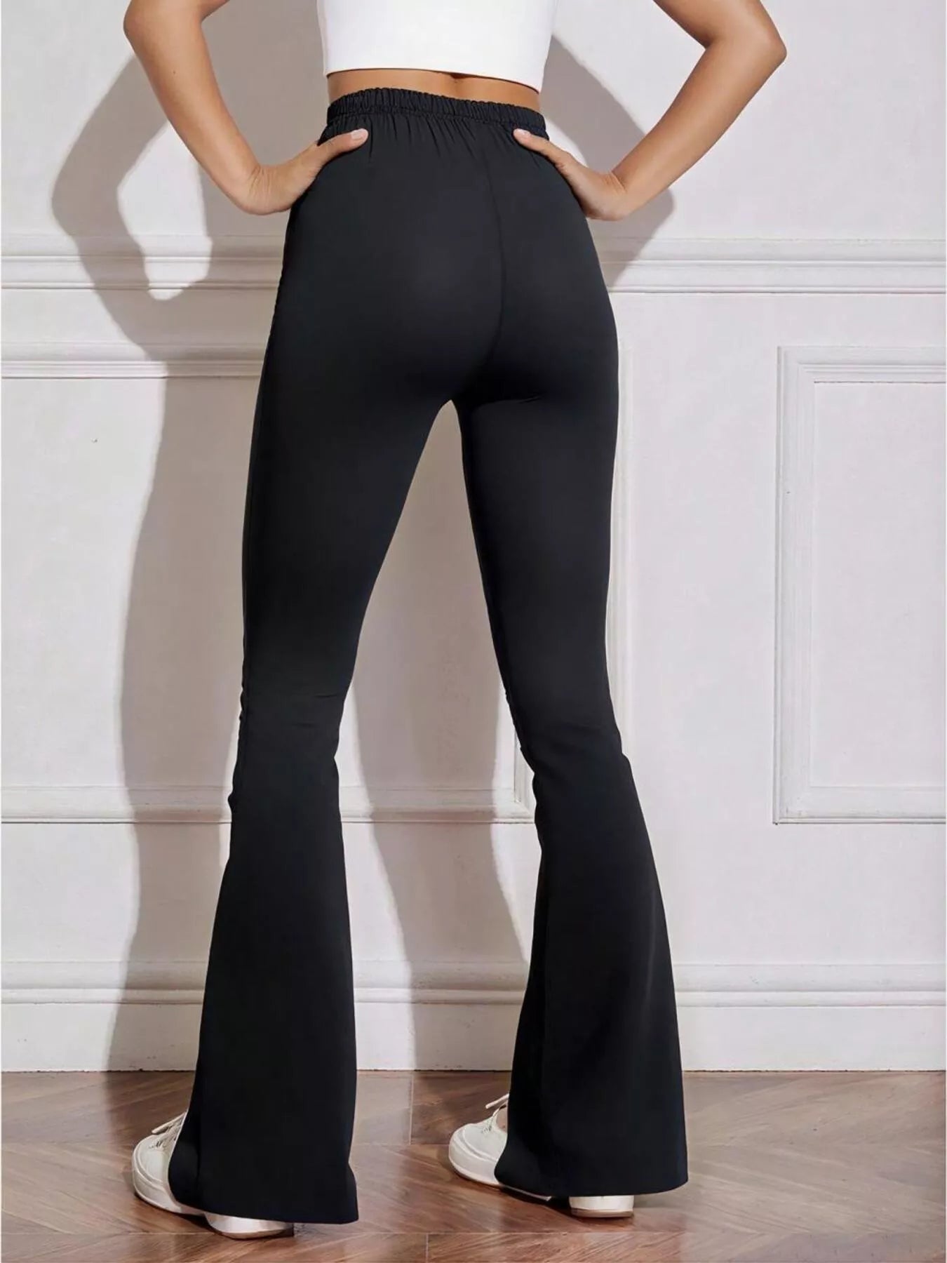Person wearing black flared pants with a white background