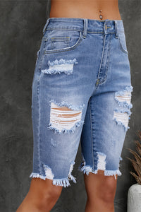 Ripped blue denim shorts on a dark background