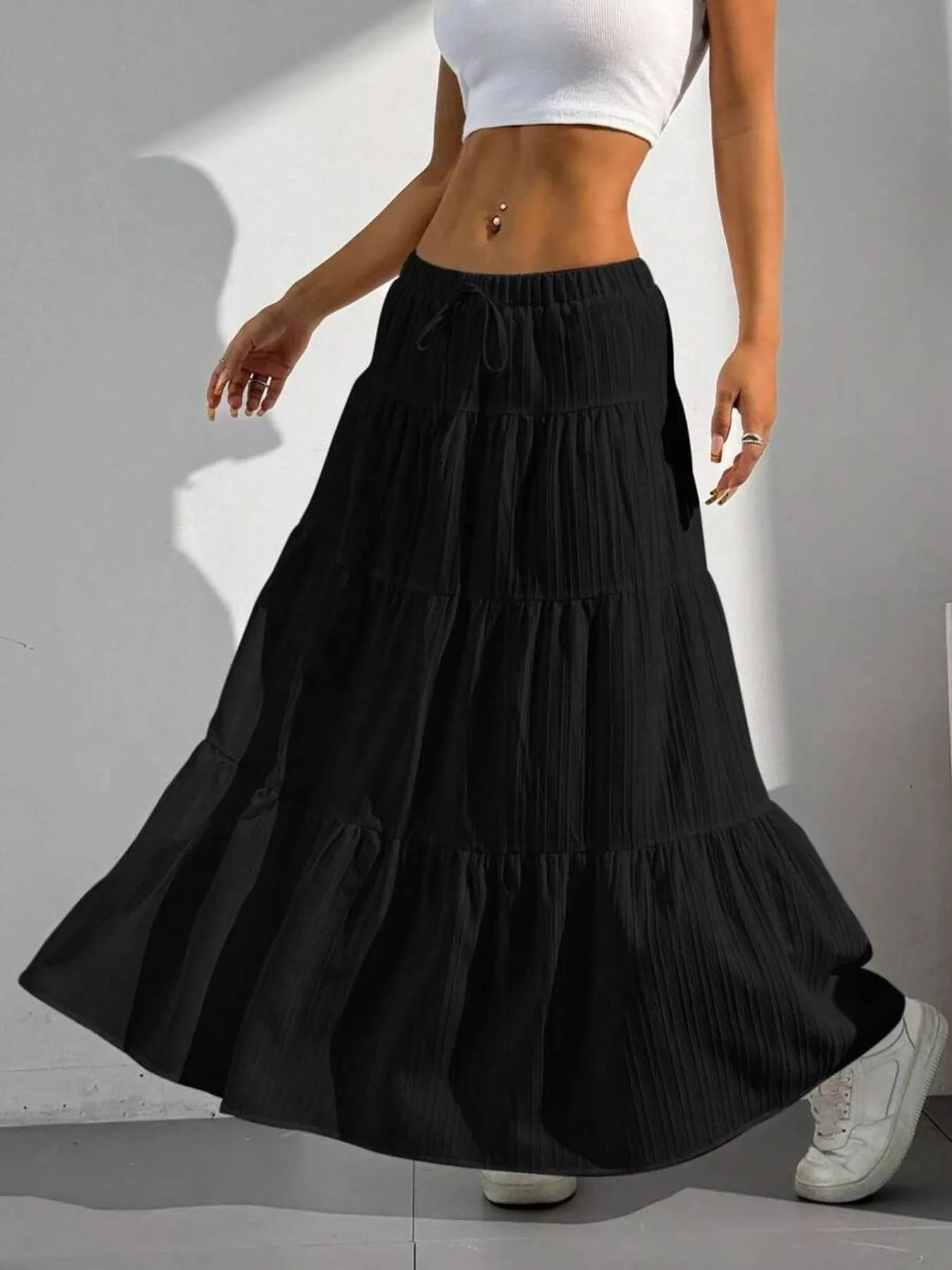 Person wearing a black tiered skirt and white top on a gray background