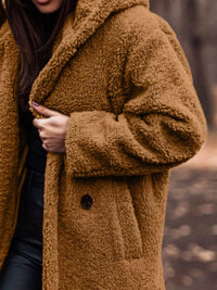 Brown teddy coat worn by a person with a blurred background