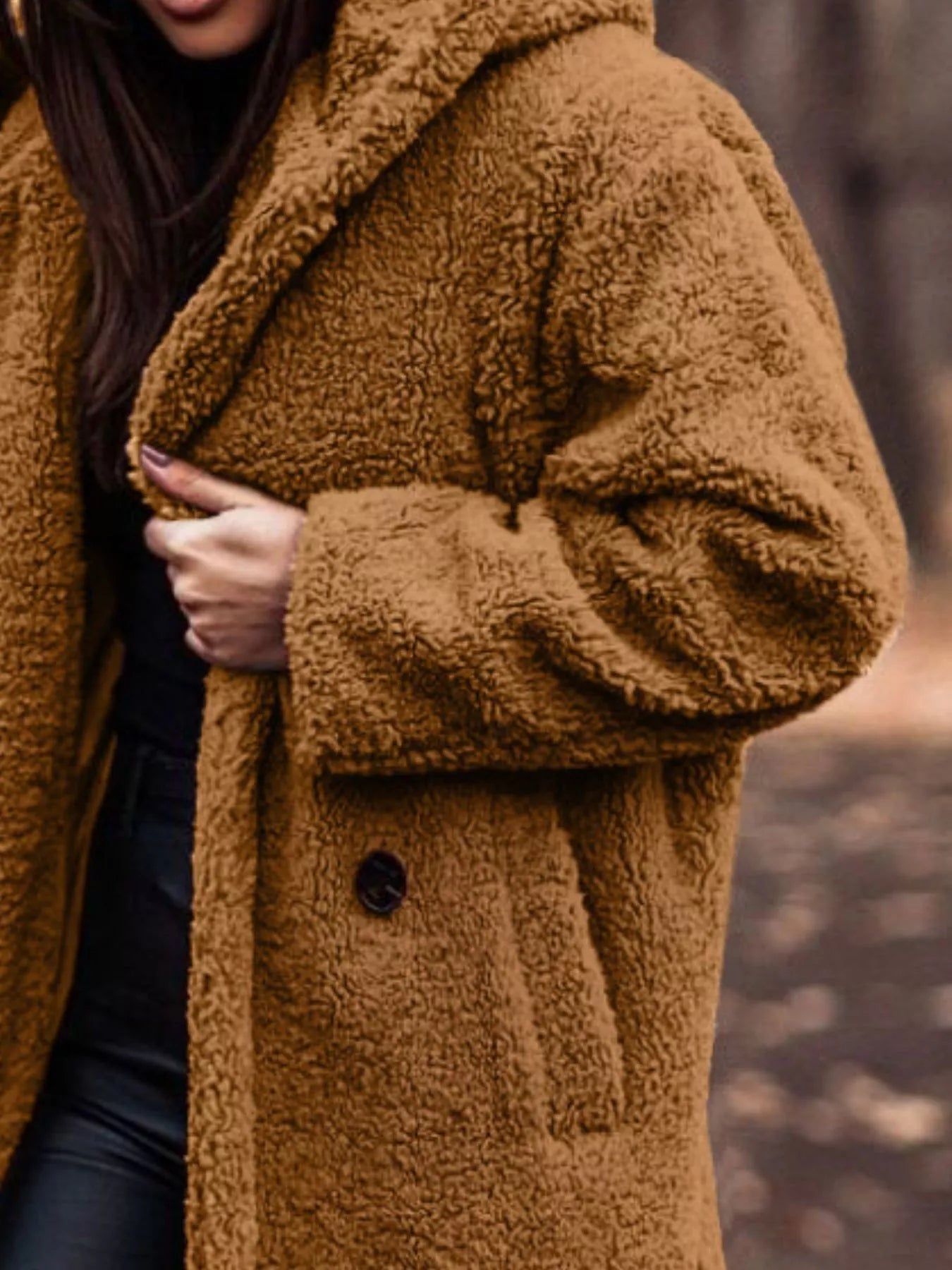 Brown teddy coat worn by a person with a blurred background