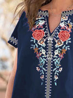 Navy blue dress with floral embroidery on a blurred natural background