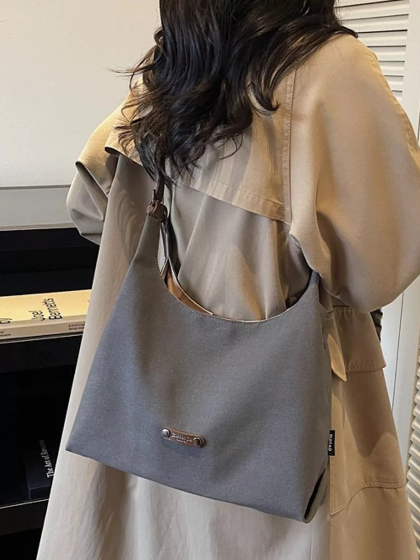 Person wearing a beige trench coat with a gray shoulder bag.