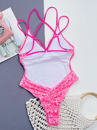Pink and white swimsuit with leopard print trim on a gray surface