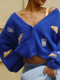 Blue knitted cardigan with yellow accents worn by a person, against a neutral background.